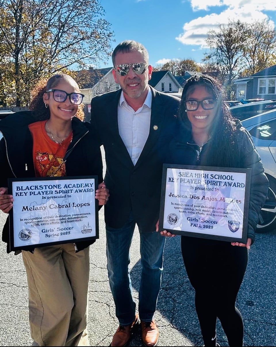 A man stands between two women holding printed boards on a sunny street.