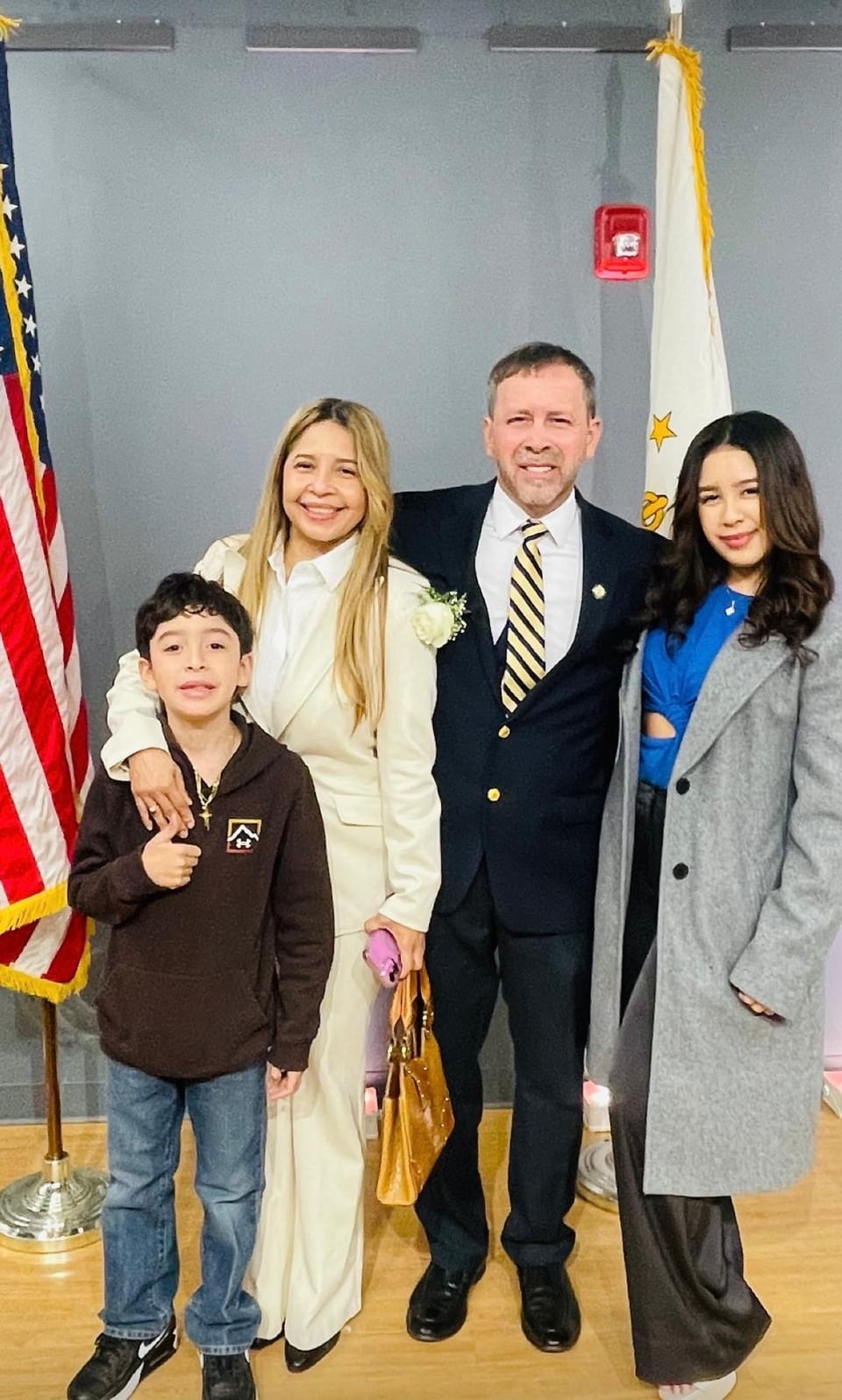 Juan Pablo Barrera poses with two women and a child between two flags.