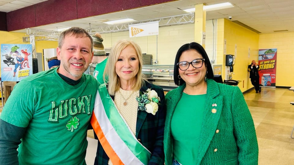 Juan Pablo Barrera poses with two women indoors; the center woman wears a white sash.