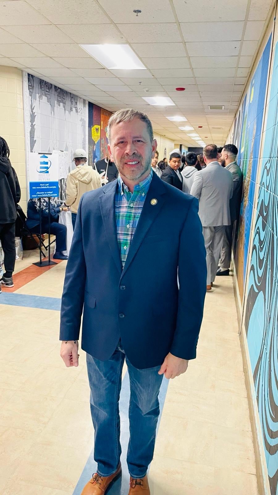 Juan Pablo Barrera stands in a busy hallway beside a wall display.