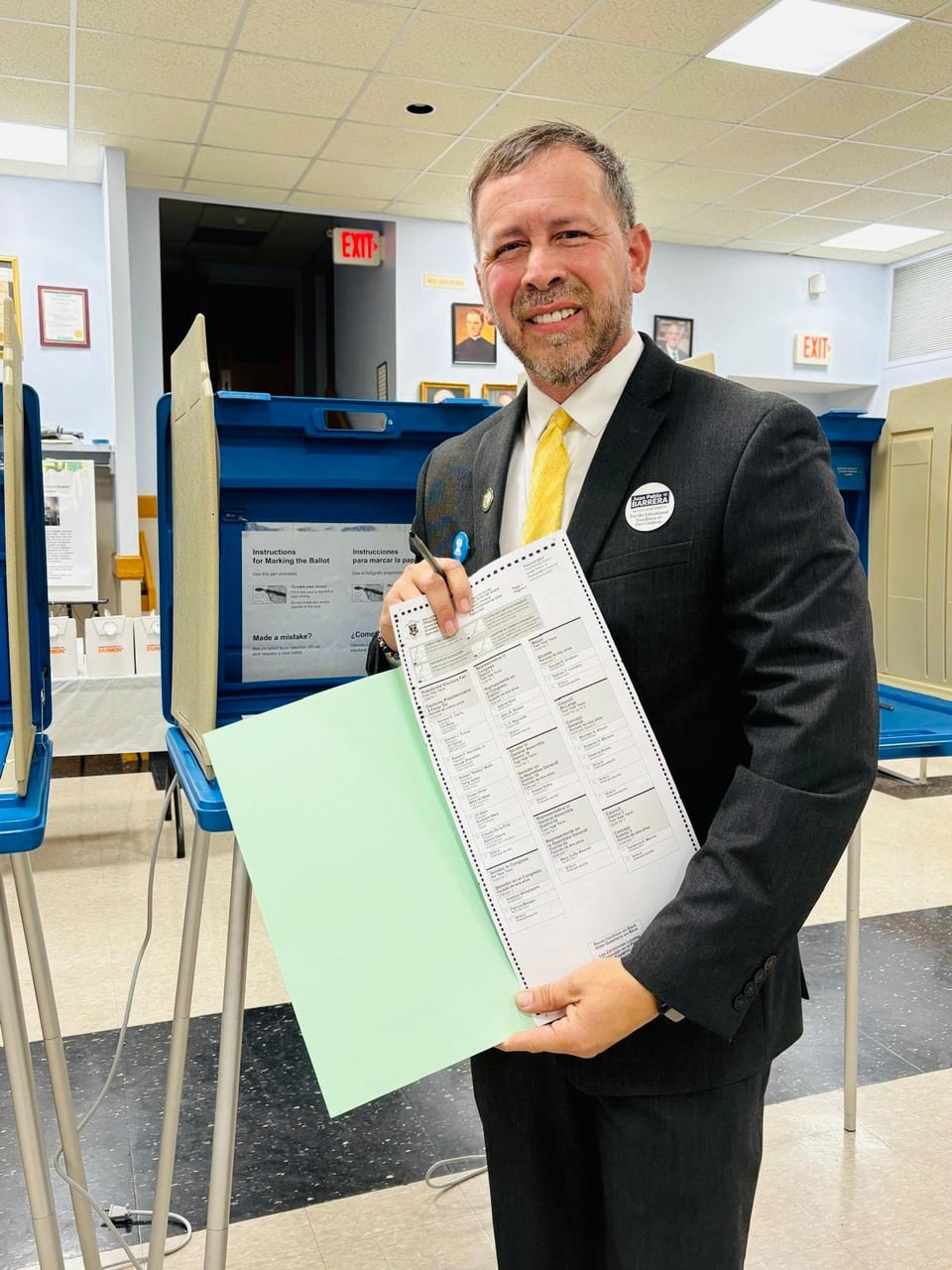 Juan Pablo Barrera smiles while holding a printed document and an open green folder.